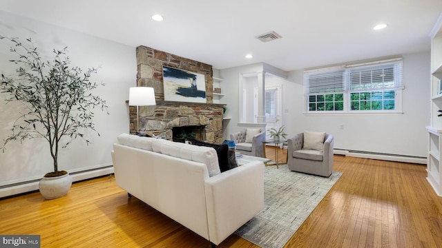 living area featuring a baseboard radiator, a stone fireplace, light wood-style flooring, and recessed lighting