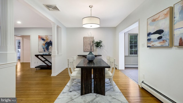 dining room with a baseboard radiator, ornate columns, light wood-style floors, baseboards, and recessed lighting