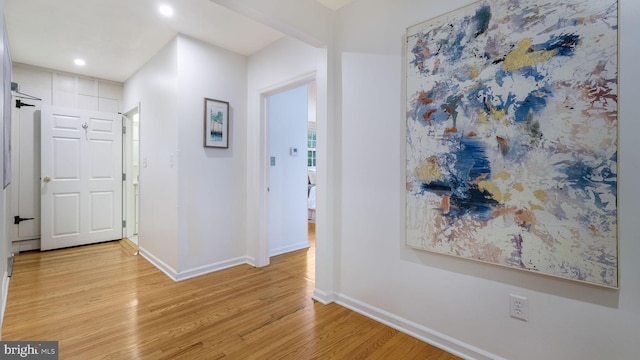 corridor with light wood finished floors, baseboards, and recessed lighting
