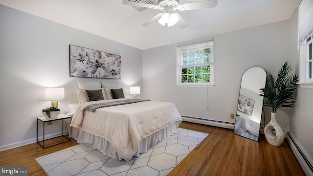bedroom with a baseboard radiator, light wood finished floors, and a ceiling fan