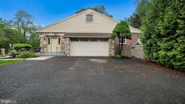 view of front of house featuring asphalt driveway, stone siding, and an attached garage