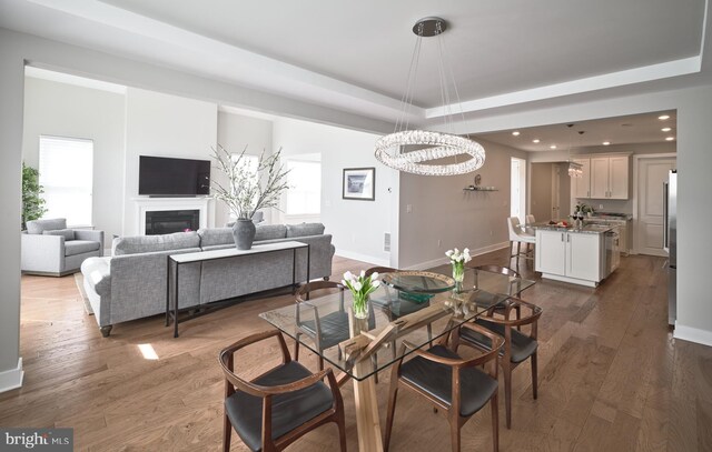 dining area featuring a tray ceiling, recessed lighting, baseboards, a chandelier, and dark wood-style floors