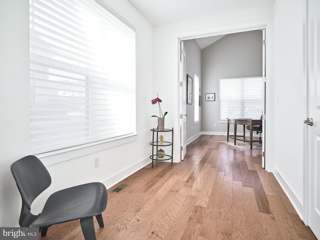 corridor with baseboards, visible vents, and wood finished floors