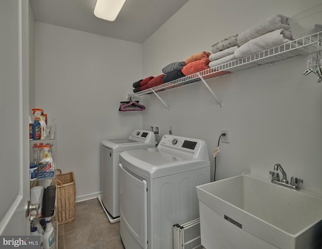 laundry room with light tile patterned floors, a sink, laundry area, washer and clothes dryer, and baseboards