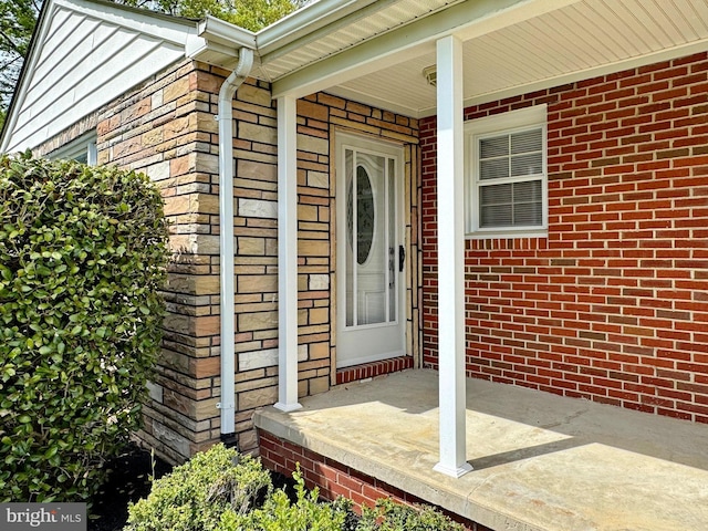 doorway to property with stone siding and covered porch
