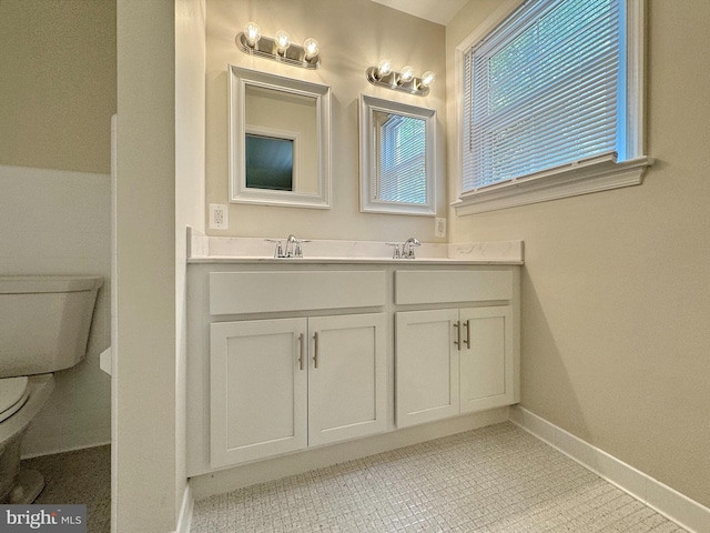 full bath featuring baseboards, toilet, double vanity, and a sink