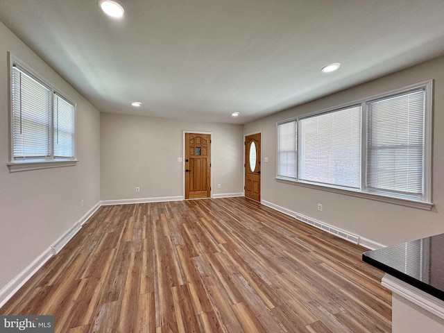 unfurnished living room featuring wood finished floors, a healthy amount of sunlight, recessed lighting, and baseboards