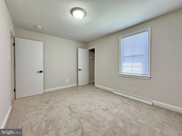 unfurnished bedroom featuring a closet, baseboards, baseboard heating, and carpet floors