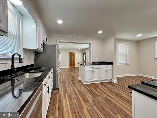kitchen featuring wood finished floors, baseboards, white cabinetry, and a sink