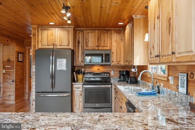 kitchen featuring appliances with stainless steel finishes, wooden walls, wood ceiling, light stone countertops, and a sink