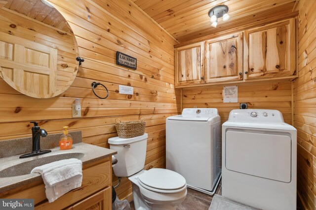 half bathroom featuring washer and clothes dryer, toilet, wooden walls, vanity, and wood ceiling