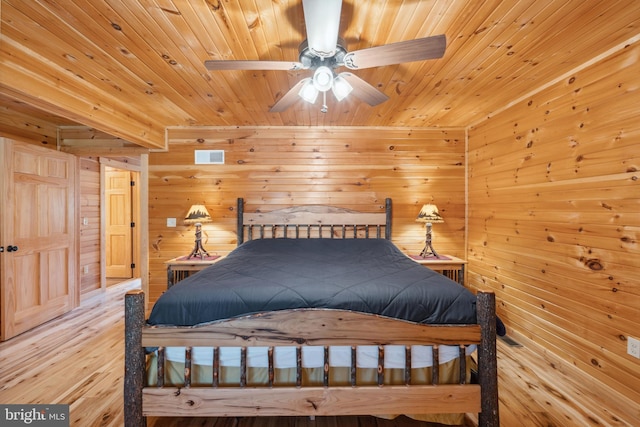 bedroom featuring wood ceiling, wooden walls, and light wood-type flooring