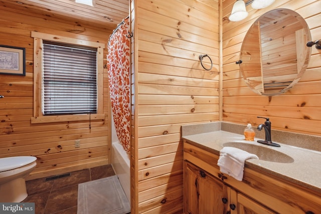 full bath with wooden walls, tile patterned flooring, toilet, vanity, and shower / tub combo