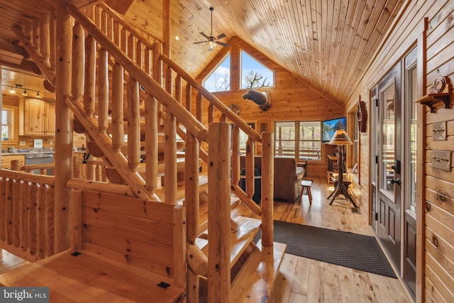 stairway with wood ceiling, healthy amount of natural light, wooden walls, high vaulted ceiling, and hardwood / wood-style floors