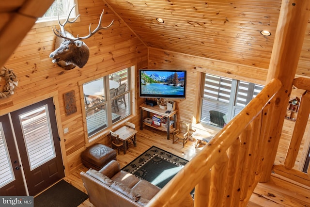 living room featuring wooden walls, wood finished floors, vaulted ceiling, and wooden ceiling