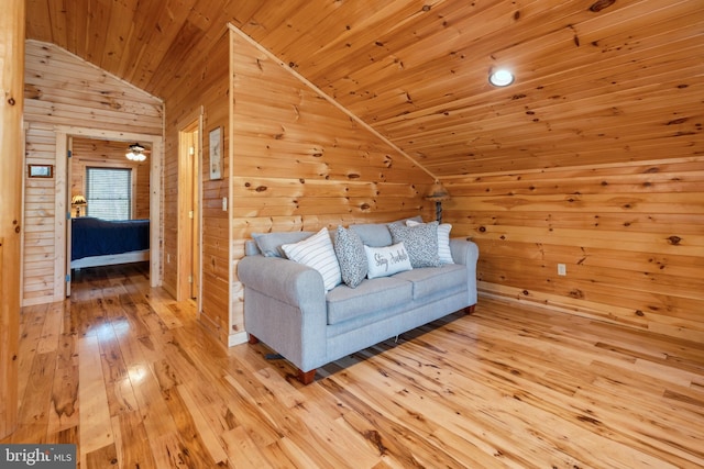living room with lofted ceiling, wood walls, wooden ceiling, and light wood-style floors