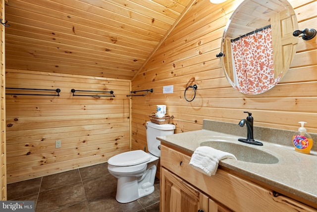 bathroom with lofted ceiling, toilet, vanity, wooden walls, and tile patterned floors