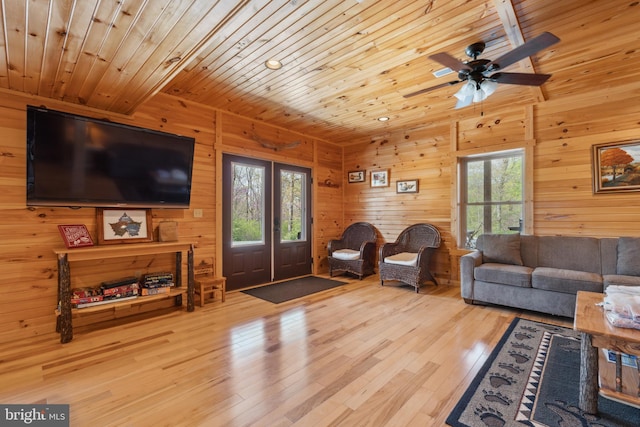 living room featuring plenty of natural light, french doors, wooden ceiling, ceiling fan, and wooden walls