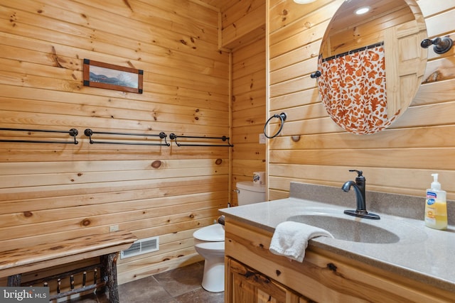 bathroom featuring toilet, wood walls, vanity, and curtained shower