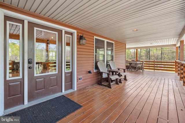 wooden deck featuring outdoor dining area and a porch