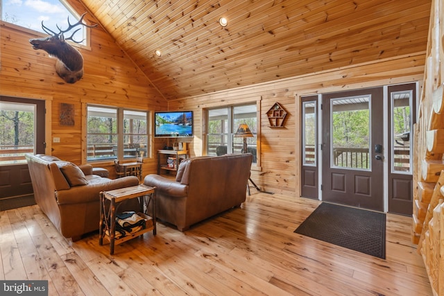 living room featuring high vaulted ceiling, wood walls, light wood-type flooring, and wood ceiling