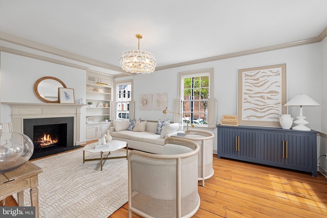201 Duke St, Alexandria, VA 22314 - living room featuring crown molding, built in features, light wood-style floors, a warm lit fireplace, and a notable chandelier