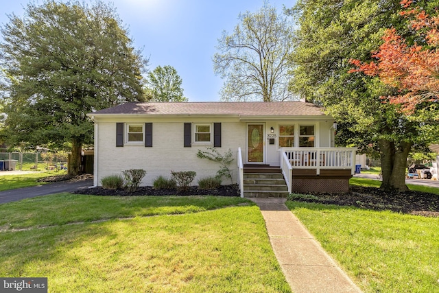 view of front of house featuring covered porch, brick siding, and a front yard