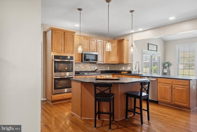 16 Zachary Ct, Boonsboro, MD 21713 - kitchen with stainless steel appliances, dark countertops, a sink, a center island, and decorative backsplash