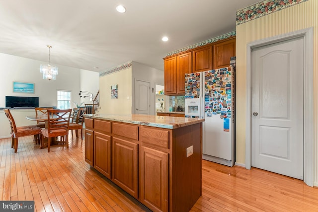 25 Stallion Cir, Upper Holland, PA 19053 - kitchen featuring light stone counters, white fridge with ice dispenser, brown cabinetry, light wood-style floors, and a center island