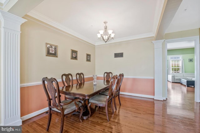 dining room featuring ornate columns, ornamental molding, baseboards, and wood finished floors