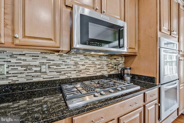 kitchen featuring backsplash, stainless steel appliances, and dark stone countertops