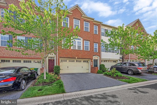 townhome / multi-family property with brick siding, an attached garage, and driveway