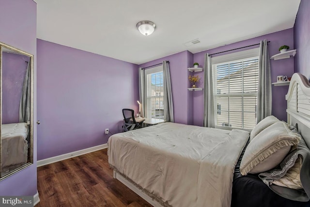 bedroom with baseboards, visible vents, and wood finished floors