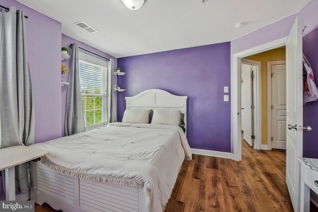 bedroom featuring baseboards, wood finished floors, and visible vents