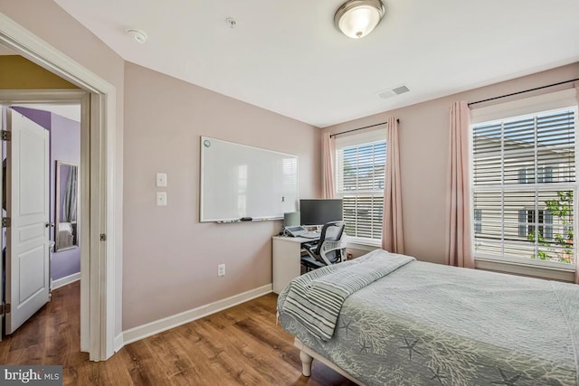 bedroom with baseboards, wood finished floors, and visible vents