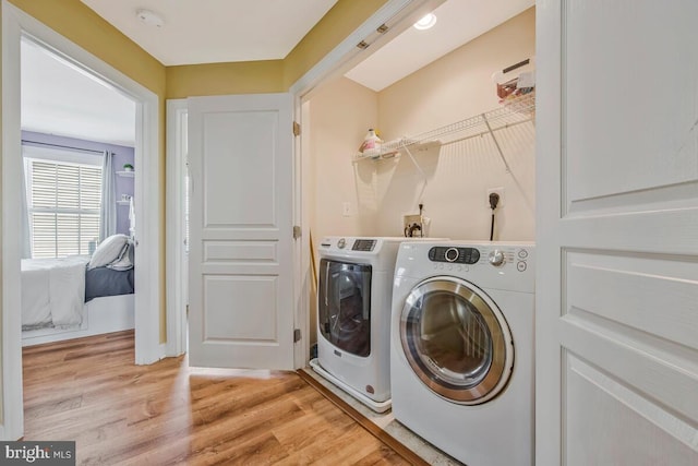 clothes washing area with laundry area, light wood-type flooring, and washing machine and clothes dryer