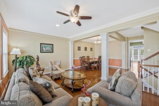 living room with ceiling fan with notable chandelier, stairs, baseboards, wood finished floors, and ornate columns