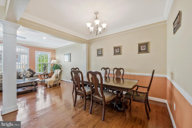dining space featuring crown molding, baseboards, decorative columns, and wood finished floors