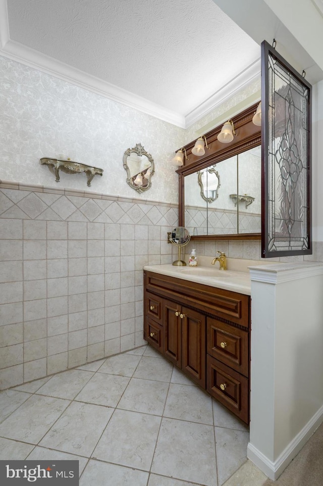 bathroom with vanity, ornamental molding, a wainscoted wall, and wallpapered walls
