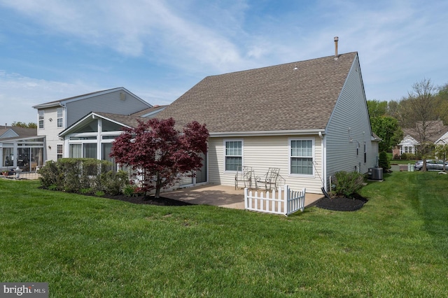 rear view of property with a yard, cooling unit, a shingled roof, and a patio area