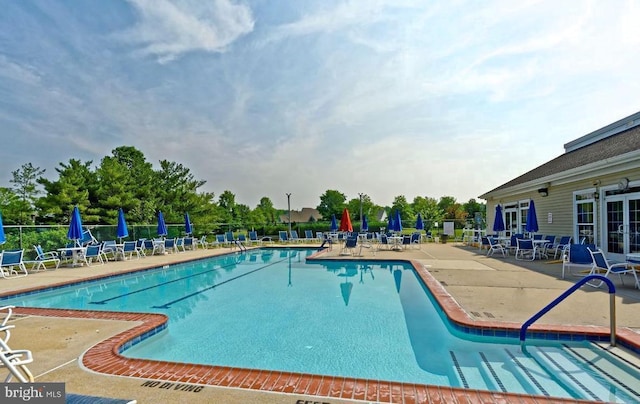 community pool with fence, a patio, and french doors