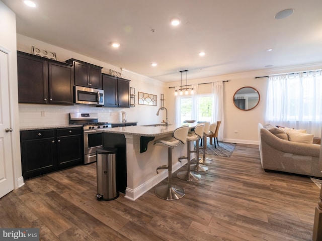 9318 Sydney Way, Laurel, MD 20723 - kitchen with light stone counters, a sink, a kitchen breakfast bar, stainless steel appliances, and dark wood-type flooring
