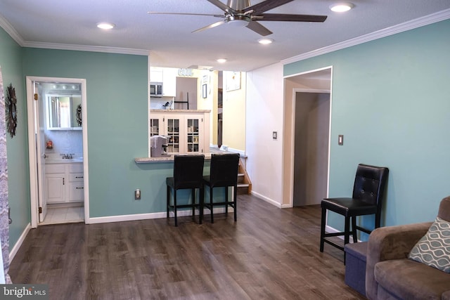 living room with dark wood-style floors, baseboards, ornamental molding, and ceiling fan