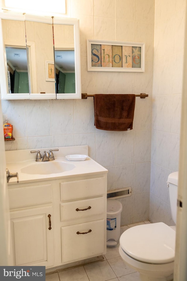half bathroom with tile patterned flooring, tile walls, toilet, vanity, and visible vents