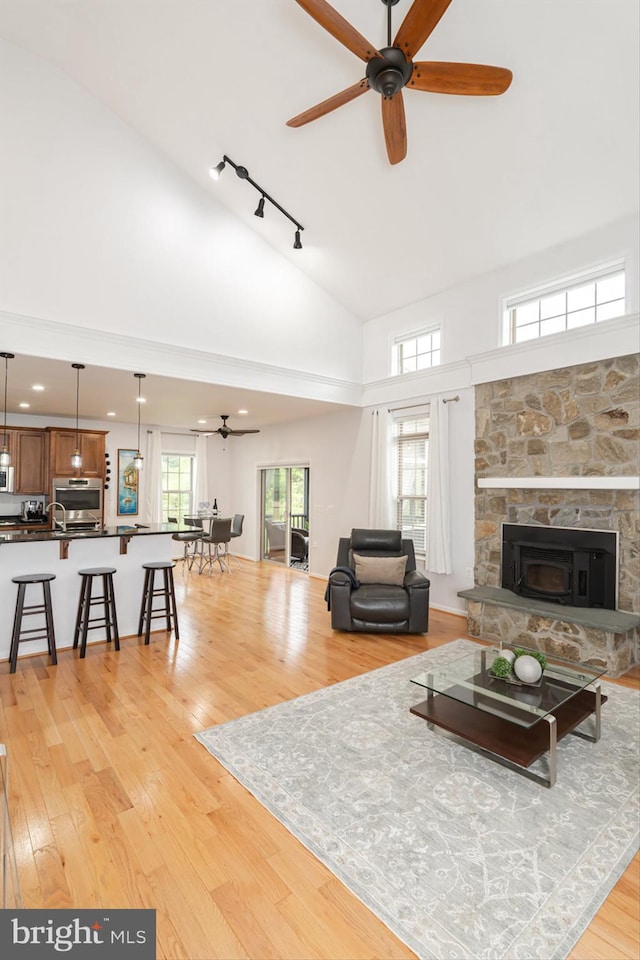 189 Potomac Crossing St, Charles Town, WV 25414 - living room with a ceiling fan, high vaulted ceiling, light wood-style floors, rail lighting, and a stone fireplace