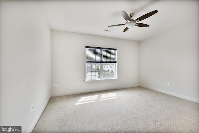 carpeted spare room featuring baseboards, visible vents, and ceiling fan