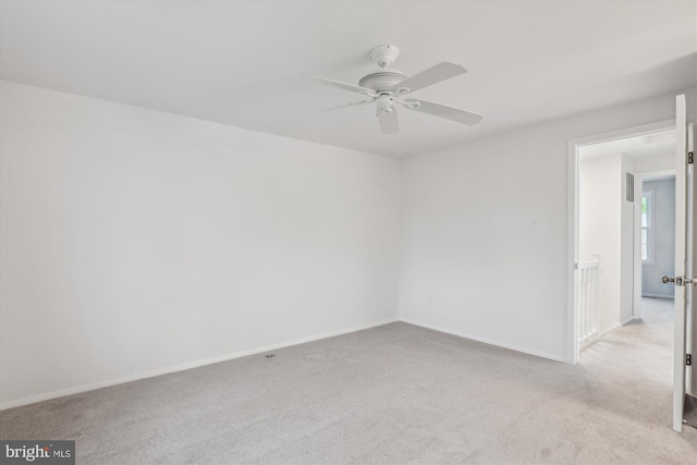 spare room featuring baseboards, light carpet, and ceiling fan