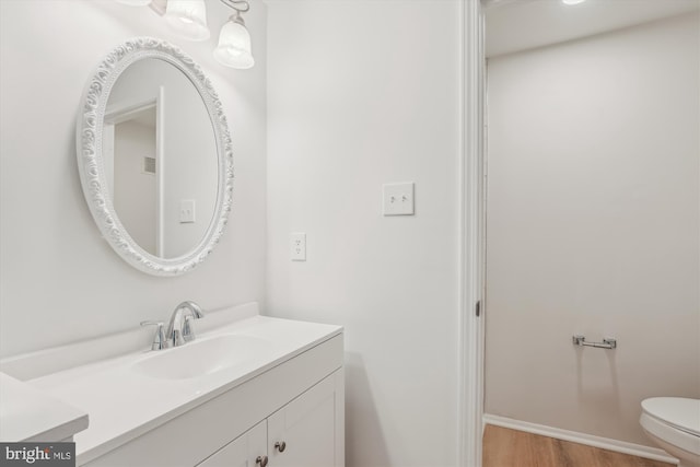 bathroom with toilet, wood finished floors, and vanity