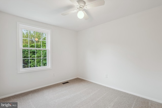 unfurnished room with a ceiling fan, visible vents, carpet, and baseboards