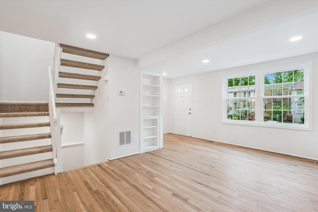 unfurnished living room with recessed lighting, visible vents, stairway, and wood finished floors